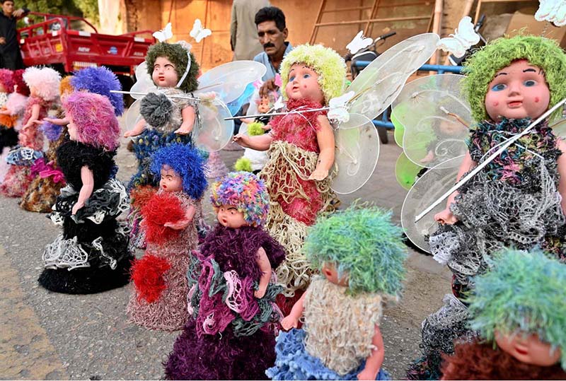 A young vendor arranging and displaying toys on footpath to attract the customers at Girls College Road