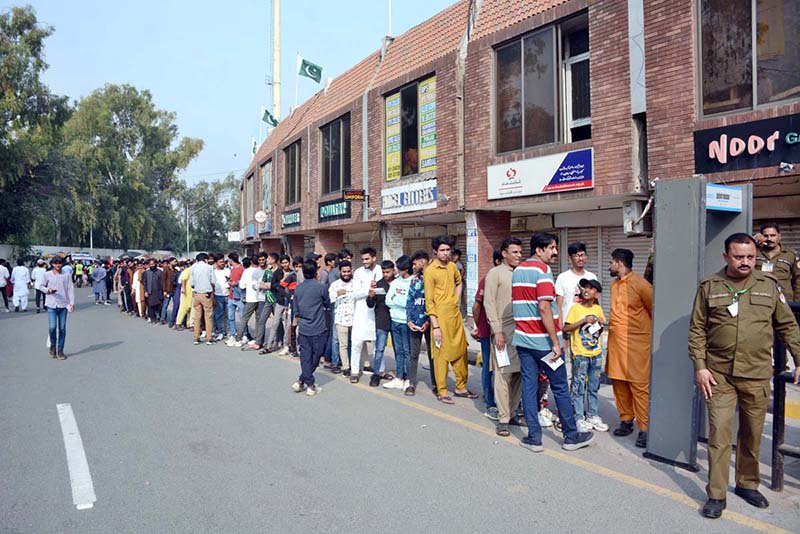 Cricket lovers stand in queue at the entry gate of Iqbal Stadium to attend the first ODI match between Pakistan and South Africa
