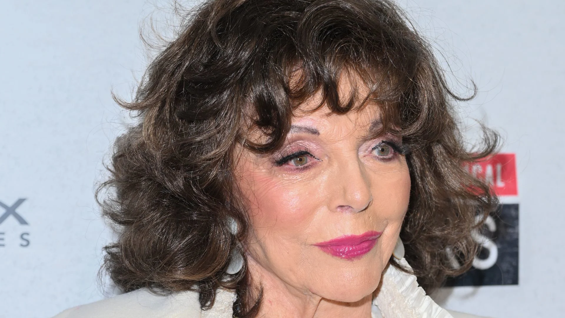 Dame Joan Collins, 92, is a doting godmother – in most incredible caped dress